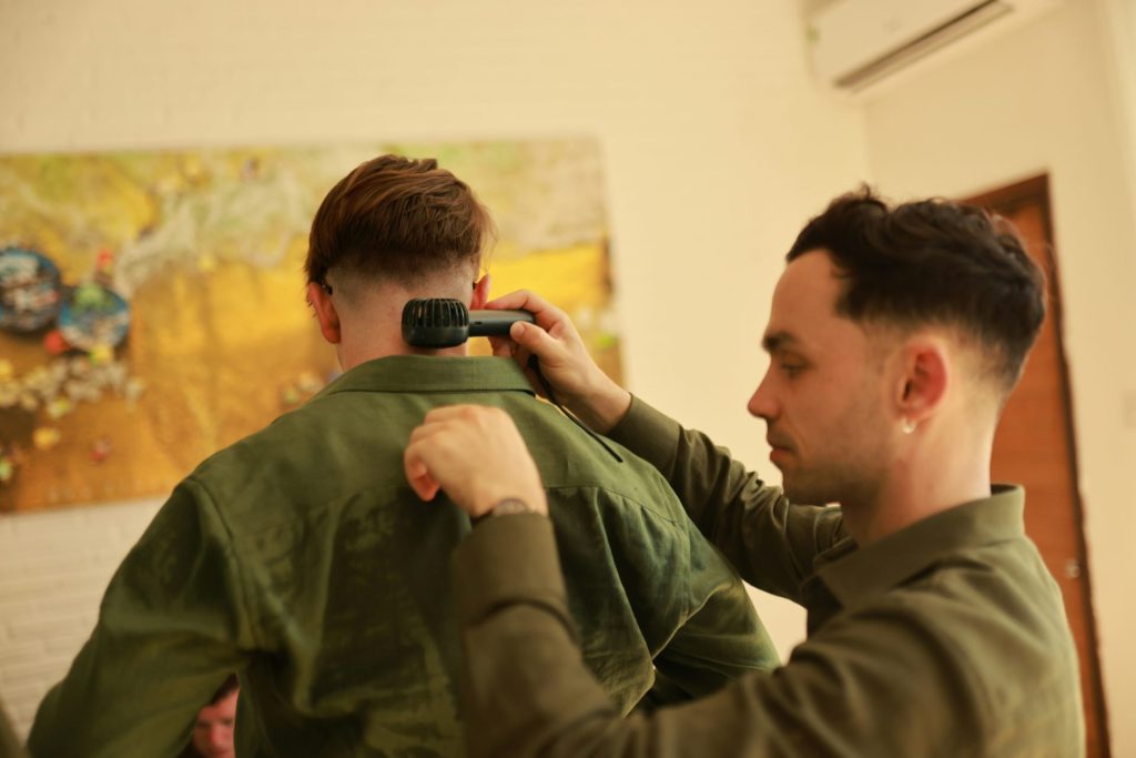 A barber trims a man's hair with a trimmer.